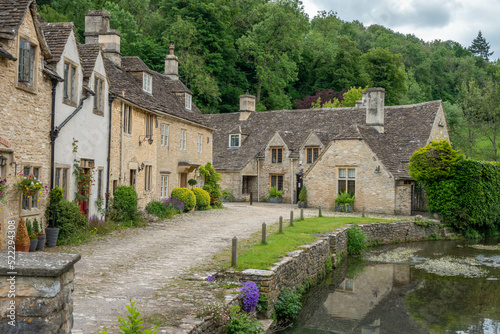 honey coloured Cotswold stone houses alongside By Brook in Castle Combe Wiltshire England often named as the prettiest village in England