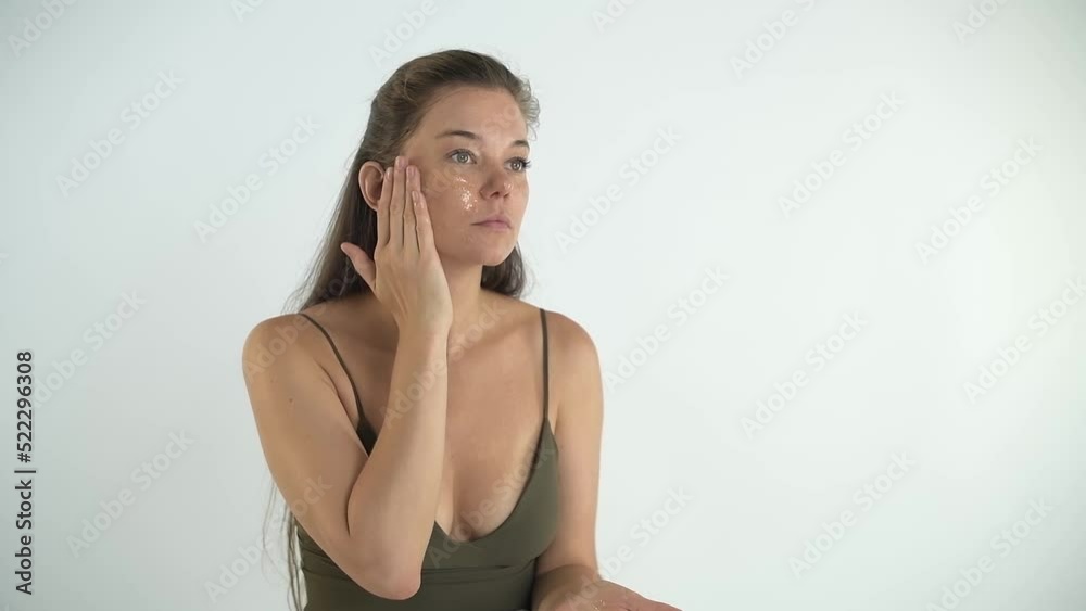 A young beautiful girl applies a transparent moisturizing mask to her face. A young beautiful girl applies a transparent moisturizing mask to her face.