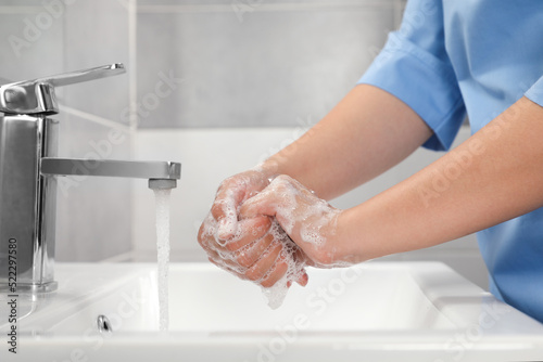 Cuadro en lienzo Doctor washing hands with water from tap in bathroom, closeup
