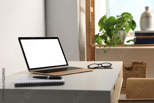 Workplace with modern laptop and glasses on white table. Mockup for design © New Africa