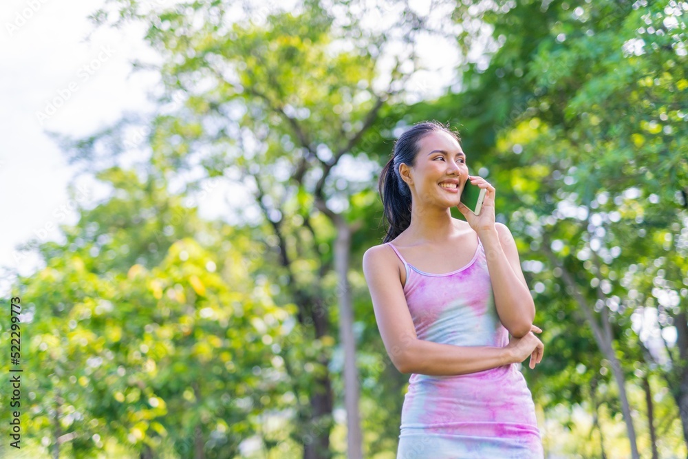 Portrait photo of the beautiful moment of a young asian beautiful lady happily talking on her phone with her friends during a garden park strolling Portrait photo of the beautiful moment of a young asian beautiful lady happily talking on her phone with her friends during a garden park strolling