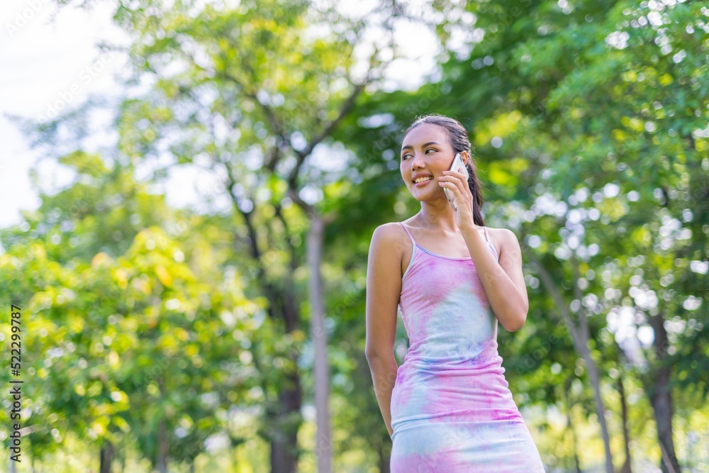 Portrait photo of the beautiful moment of a young asian beautiful lady happily talking on her phone with her friends during a garden park strolling Portrait photo of the beautiful moment of a young asian beautiful lady happily talking on her phone with her friends during a garden park strolling