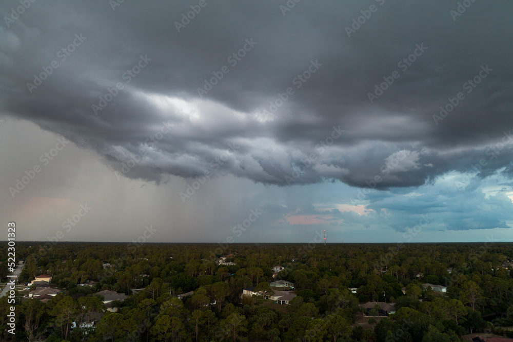 Landscape of dark ominous clouds forming on stormy sky before heavy thunderstorm over rural town area Landscape of dark ominous clouds forming on stormy sky before heavy thunderstorm over rural town area