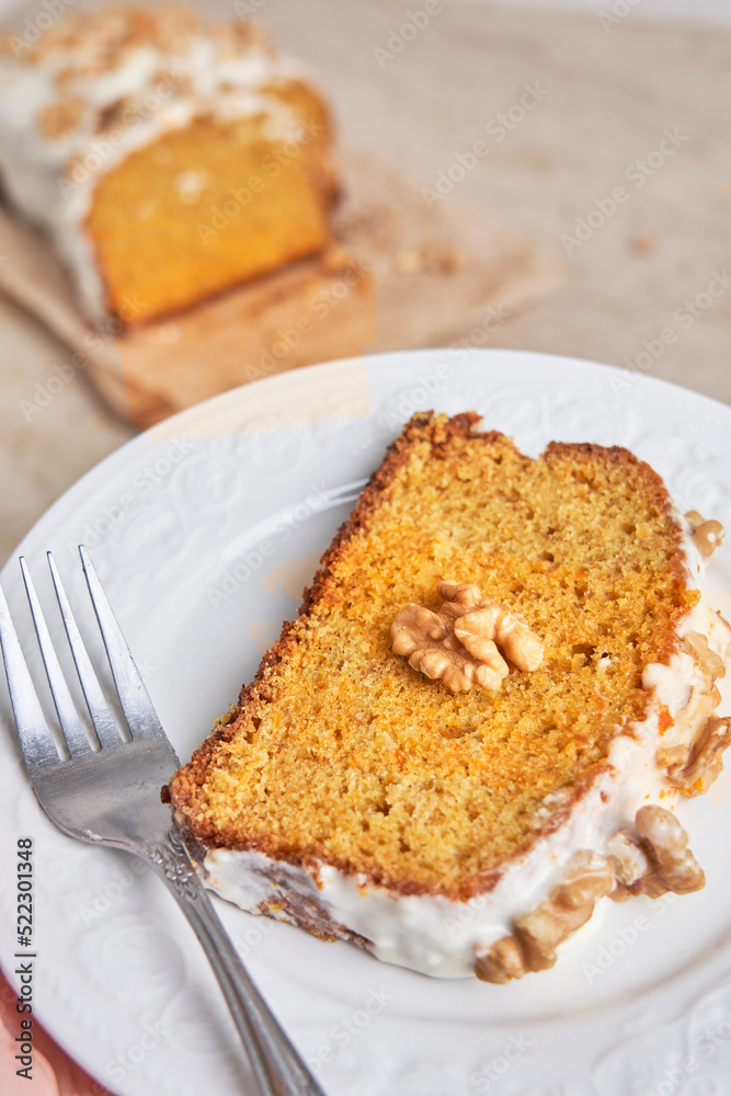 Slice of homemade carrot cake with sugar frosting and nuts on a white plate. Food concept Slice of homemade carrot cake with sugar frosting and nuts on a white plate. Food concept