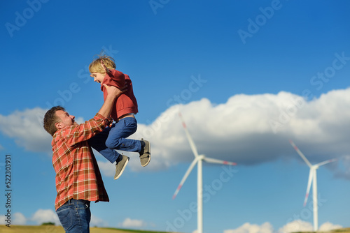 Eco activists man and child on background of power stations for renewable electric energy production. People and windmills. High wind turbines for generation electricity. Green energy