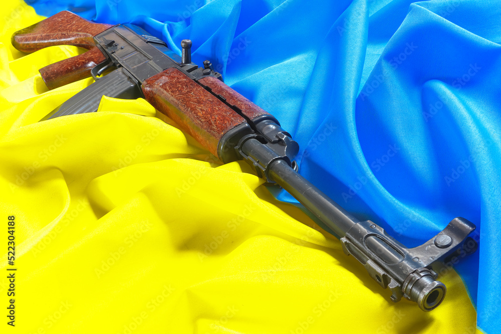The old assault rifle lying on the Ukrainian flag symbolizes resistance ...