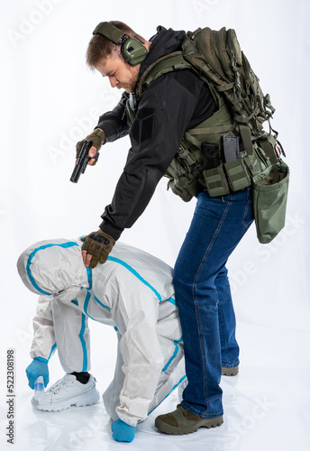 a soldier in full gear with a pistol captured a man in chemical protection, a scientist. a man in headphones, a bulletproof vest, with a backpack and a belt aims at the criminal. White background.