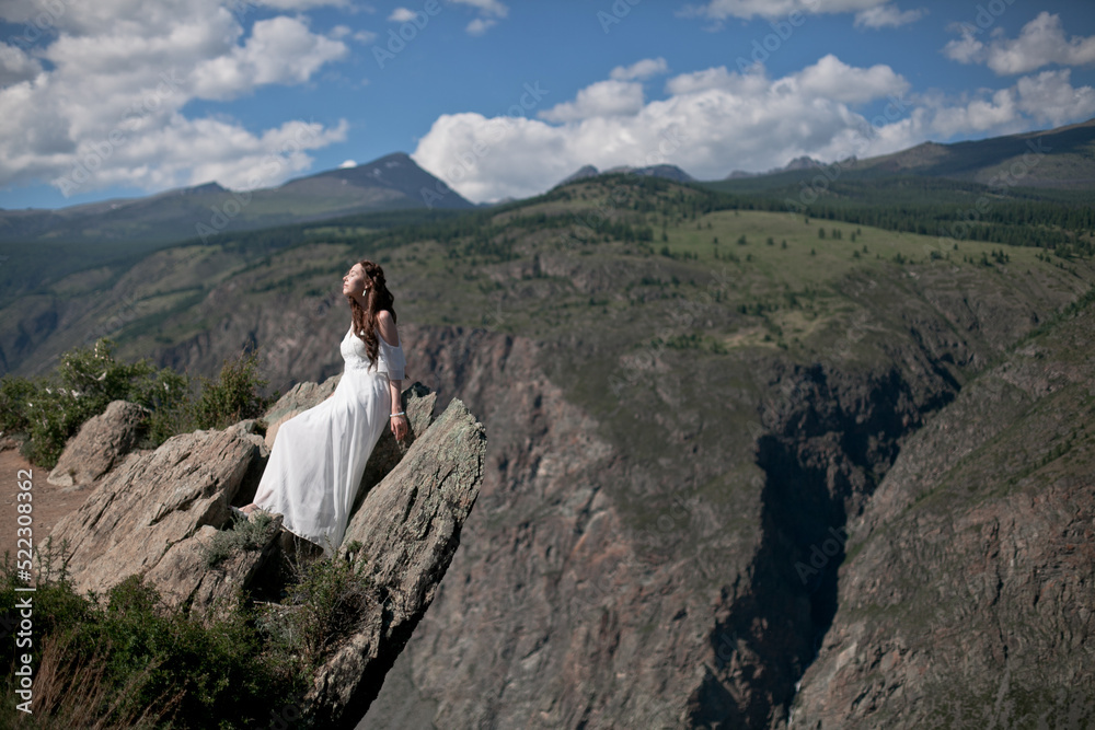 Bride in the mountains wedding image. A beautiful young woman in a wedding dress walks in the mountains.