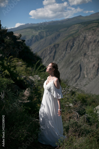 Bride in the mountains wedding image. A beautiful young woman in a wedding dress walks in the mountains.