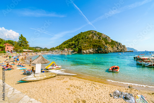 Fototapeta Naklejka Na Ścianę i Meble -  A sunny day at Palaiokastritsa beach as tourists sunbathe and swim in the sea on the island of Corfu, Greece.
