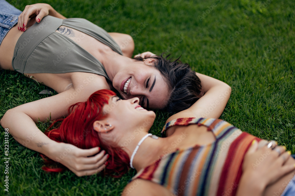 Beautiful female couple, spending time in the park, laying on the grass. Beautiful female couple, spending time in the park, laying on the grass.