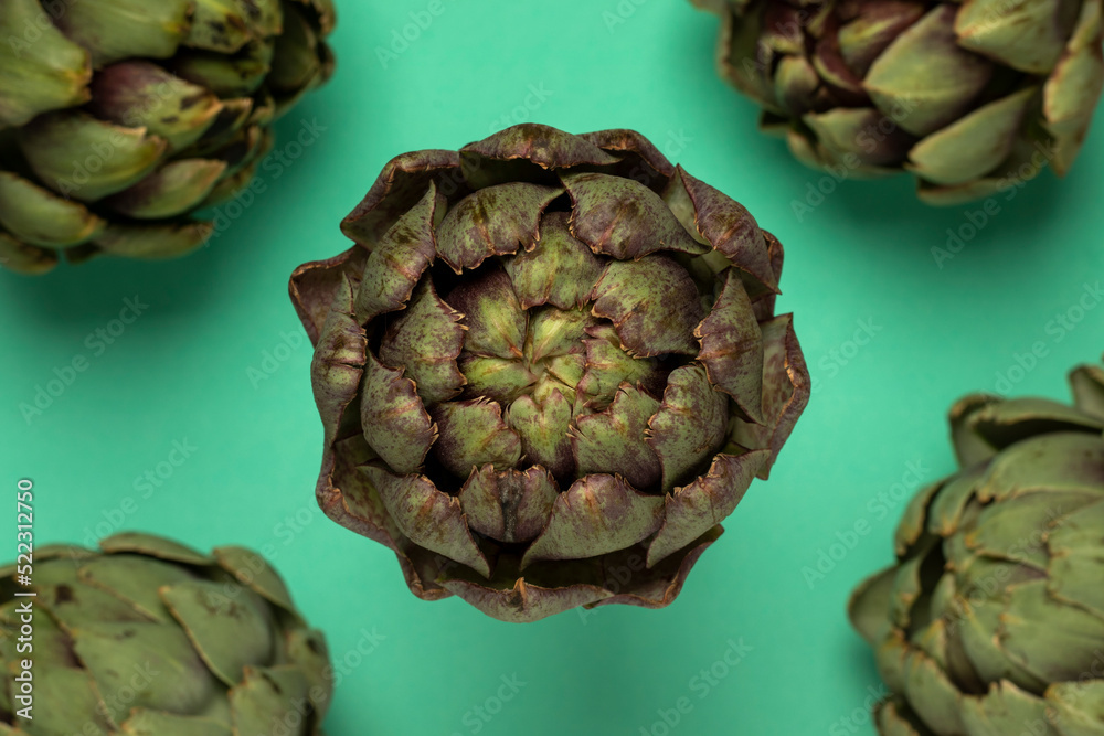 Fototapeta premium Big fresh artichokes on green background. Top view.