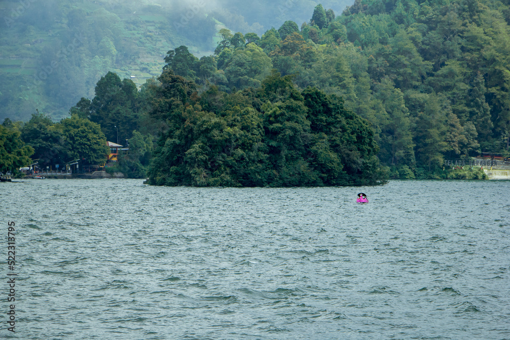 Natural panoramic portrait. Sarangan Lake with fog and boats in the morning.