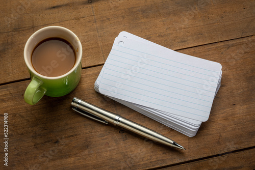 a stack of blank index cards with a cup of coffee and  a pen against textured bark paper photo