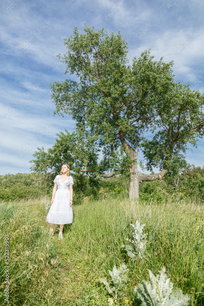 Beautiful girl in a white dress with flowers in a field overlooking the sky Beautiful girl in a white dress with flowers in a field overlooking the sky