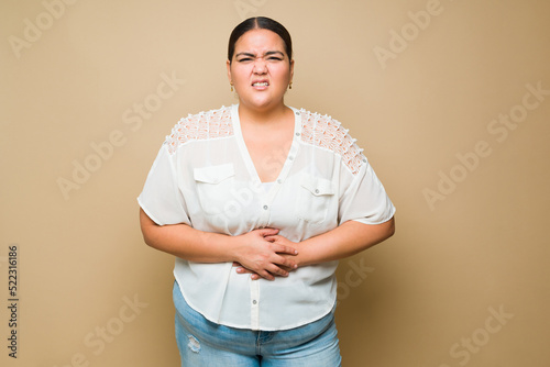 Ill fat woman suffering pain from a stomachache or indigestion photo