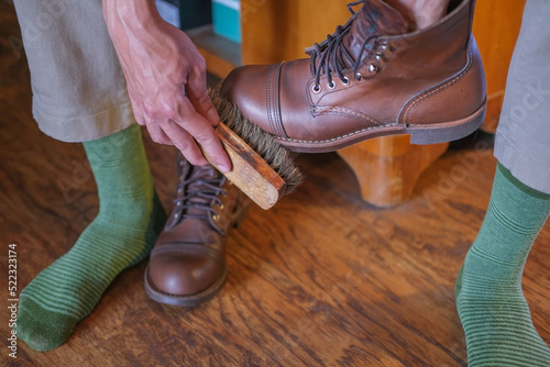 hands of a man cleaning a leather stylish shoe with a shoe brush close-up at home, shoe care