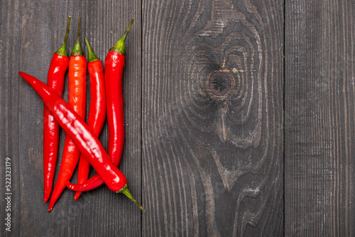 five red chili peppers on a wooden background top view