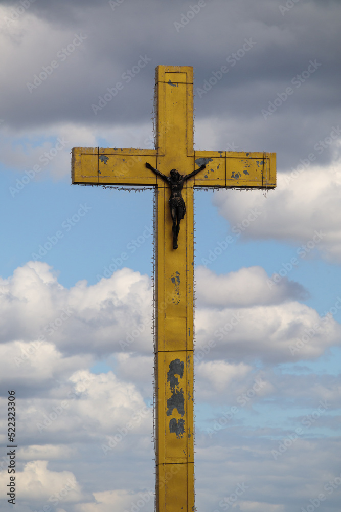A large golden cross on a background of clouds