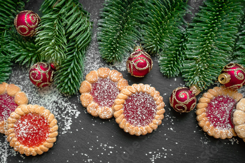 honey cookies, red baubles and fir branches on dark surface background Christmas and New Year background
