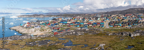 Greenland view of colorful houses in Ilulissat City and icefjord. Tourist destination in the arctic. Panoramic photo of typical Greenland village houses. Rodebay