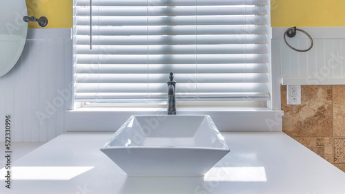 Panorama White ceramic vessel sink with antique faucet fixture against the window with blinds