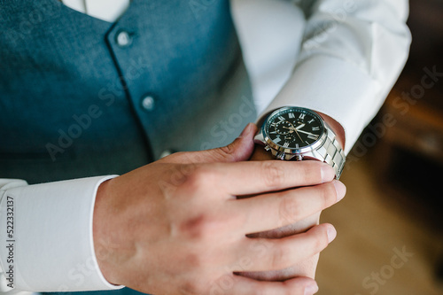 A man in a shirt adjusts the watch on his arm. Close up of businessman using watch.