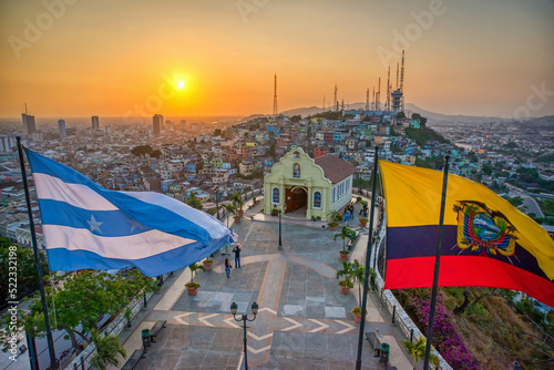 Guayaquil, Guayas, Ecuador - November, 2013: View from the lighthouse at the top of the Saint Ana hill, with a chapel and the Province and National flags waving in the wind. Warm sunset. 
