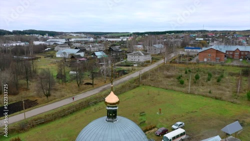 Aerial view of a traditional orthodox church in a summer village. Clip. Flying above countryside area with small houses. photo