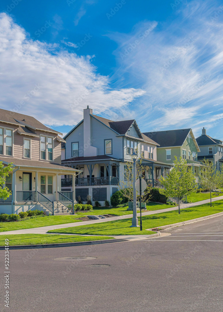 Vertical Whispy white clouds Row of large two-storey houses near the paved uphill road at Daybreak, Utah Vertical Whispy white clouds Row of large two-storey houses near the paved uphill road at Daybreak, Utah