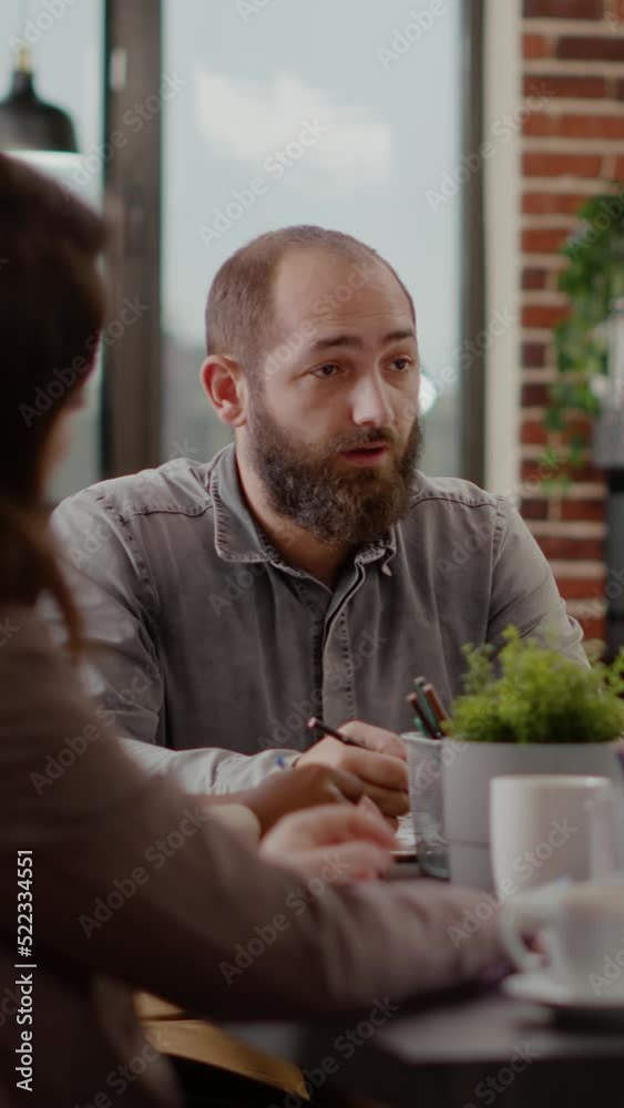 Vertical video: Close up of employee meeting with coworkers for project planning in office. Man talking to workmates to design marketing strategy, brainstorming ideas and using documents with Vertical video: Close up of employee meeting with coworkers for project planning in office. Man talking to workmates to design marketing strategy, brainstorming ideas and using documents with