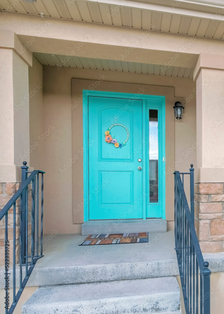 Fototapeta premium Vertical Facade of a house with cyan front door and stairs with metal railings