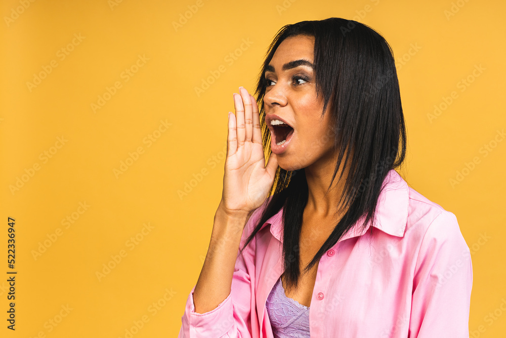 Surprised happy young african american woman stands in big shopping mall, glad to see big discounts on clothes, expresses shock, keeps hands near head, going to spend much money today.