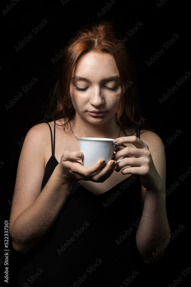 The girl drinks tea on a brown background. Enjoy a hot drink. Portrait of a young girl The girl drinks tea on a brown background. Enjoy a hot drink. Portrait of a young girl