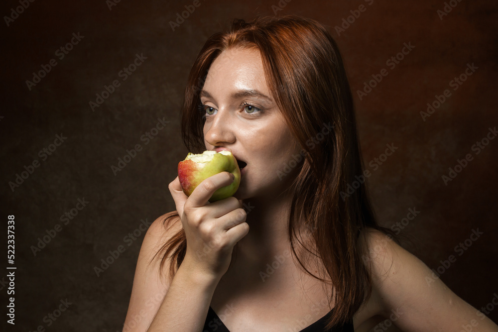 Girl eats an apple on a brown background. Healthy diet. Portrait of a young girl Girl eats an apple on a brown background. Healthy diet. Portrait of a young girl
