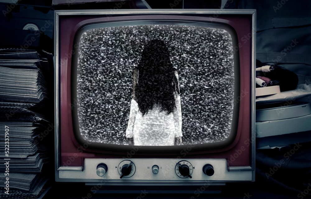 A television set in a room at night, showing static noise and a female