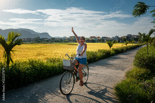 Mujer ciclista divirtiendose en un paseo por los arrozales de Ninh Binh, en Vietnam	 photo