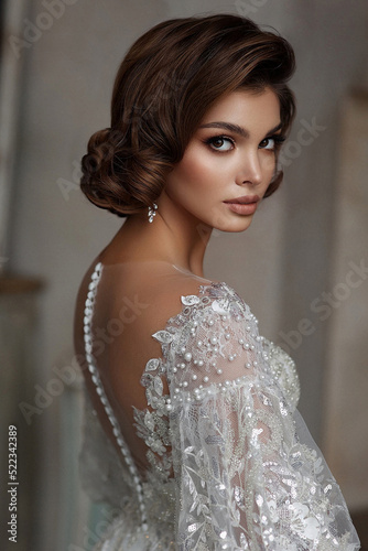 Fashion Beautiful Bride in wedding luxury dress with lace and crystals at arabian style interior. Portrait of Brunette happy woman wears bridal white dress with wedding makeup and hairstyle. Newlywed