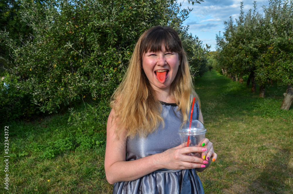 Beauty joyful girl with cold fresh lemonade, shows red tongue. Vacation holiday relax concept. Beauty joyful girl with cold fresh lemonade, shows red tongue. Vacation holiday relax concept.