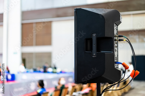 The black speaker set against a white wall with blurred background is used for voice acting in sports stadiums. The sound is clear and loud, so the action of the match can be heard clearly. photo