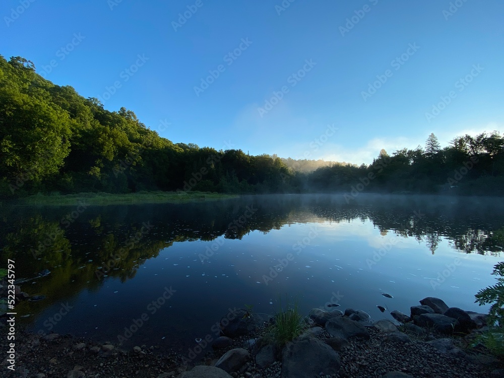 Paysage calme d'une forêt et de l'eau d'une rivière à l'aube. Reflet d'une montagne sur un lac au petit matin. Lever de soleil avec brume sur l'eau. Paysage calme d'une forêt et de l'eau d'une rivière à l'aube. Reflet d'une montagne sur un lac au petit matin. Lever de soleil avec brume sur l'eau.