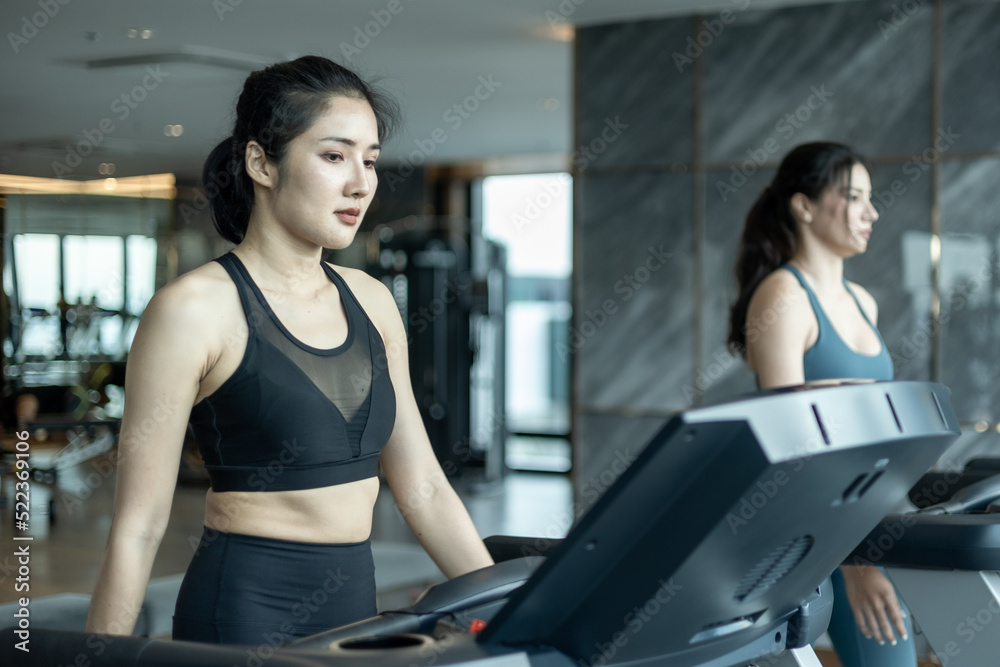 woman working out in gym, Two young Asian women jogging on a treadmill in gym, Female athlete running on a treadmill woman working out in gym, Two young Asian women jogging on a treadmill in gym, Female athlete running on a treadmill