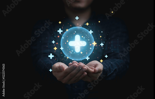 Businessman holding glowing plus sign icon which it symbol of healthcare insurance and offer positive thinking mindset of personal development concept. photo