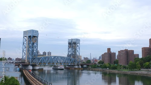 Cinematic steadycam panning ground shot along the Harlem River of NYC, a tourist cruise boat comes under the Park Avenue Bridge, view of housing projects on the Harlem riverbank photo