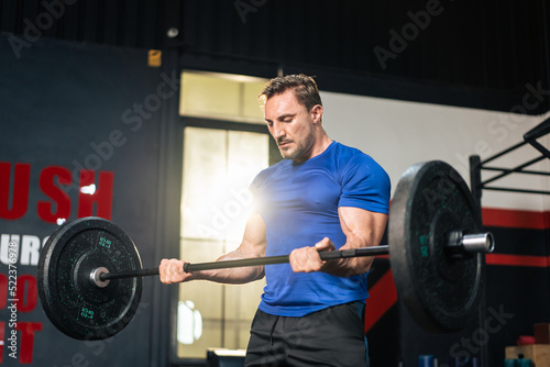 Caucasian sportsman slowly lift up weight machine barbell in stadium. 