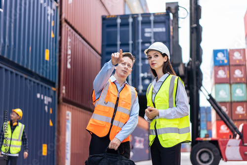 Caucasian business man and woman worker working in container terminal. 