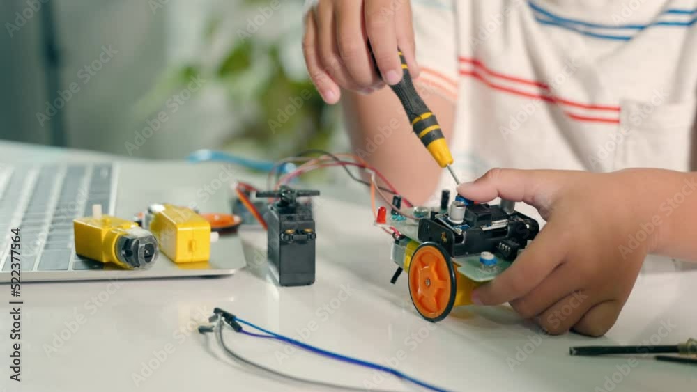 Little child tighten the nut with a screwdriver to assemble car toy ...