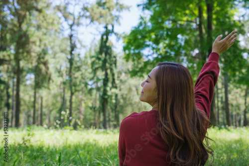 Portrait image of a beautiful young woman raising hand while sitting and relaxing in the park