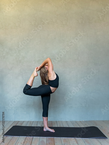 A young girl in sportswear does yoga, fitness at home, sports at home, stretching