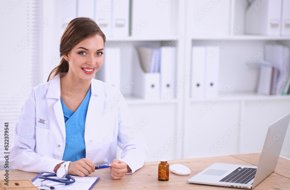 Female doctor sitting on the desk and working a laptop Female doctor sitting on the desk and working a laptop